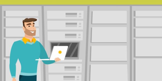 Engineer working on laptop in network server room.